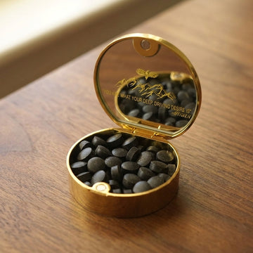 Open gold Meru tin with shilajit tablets on a walnut table in morning light