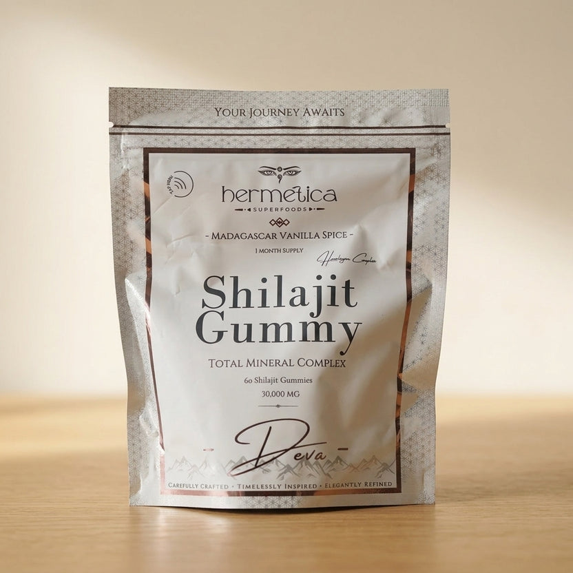 Deva Shilajit Gummies pouch on a walnut desk beside water and a linen notebook