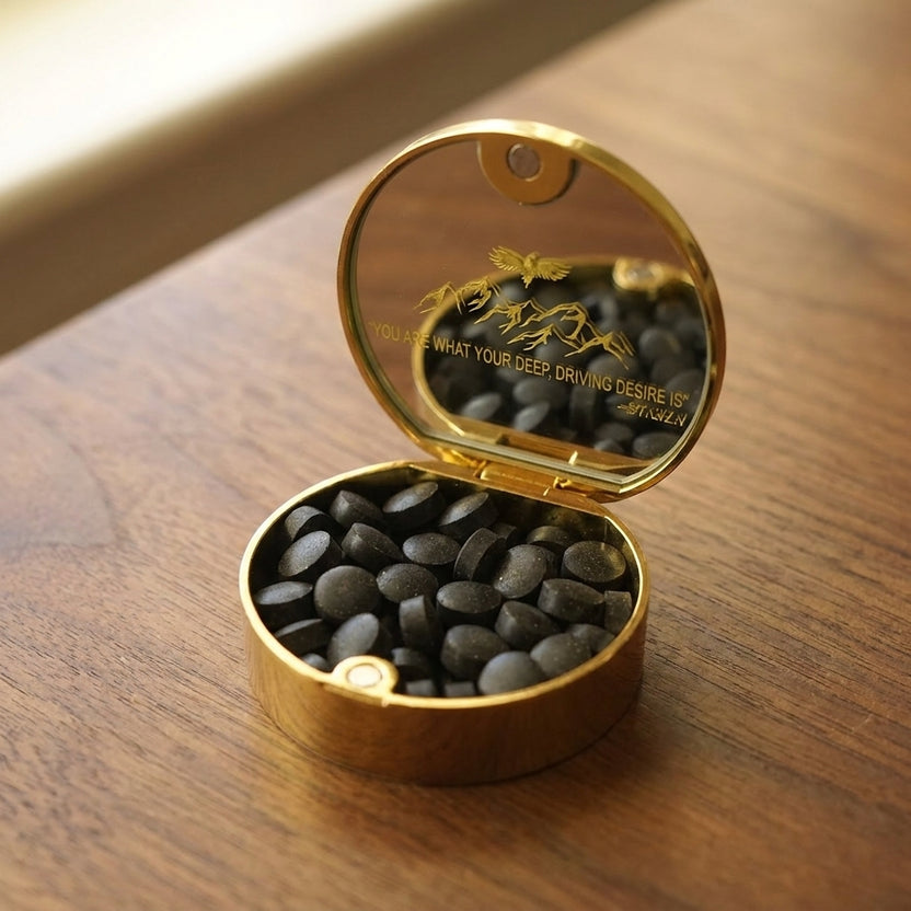 Closed gold Meru tin on a leather desk pad beside a fountain pen