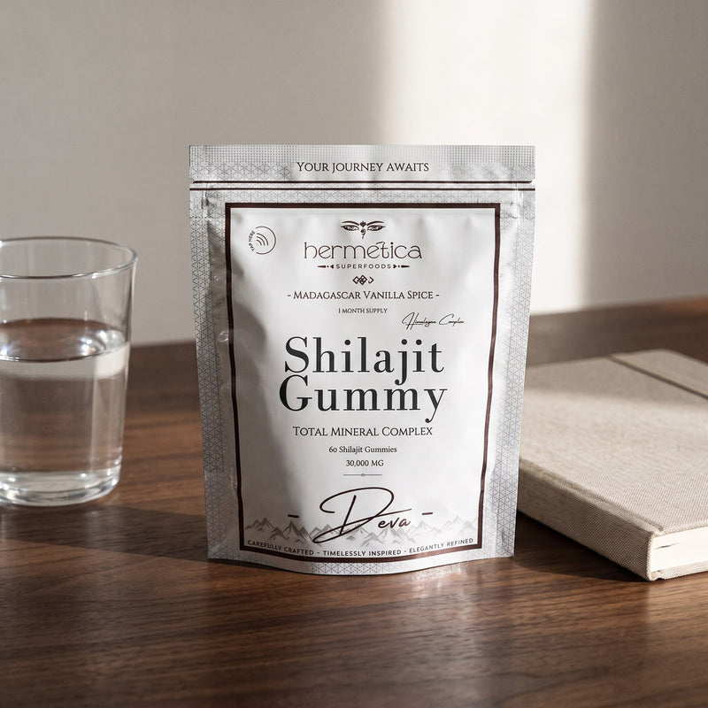 Deva Shilajit Gummies pouch on a walnut desk beside water and a linen notebook
