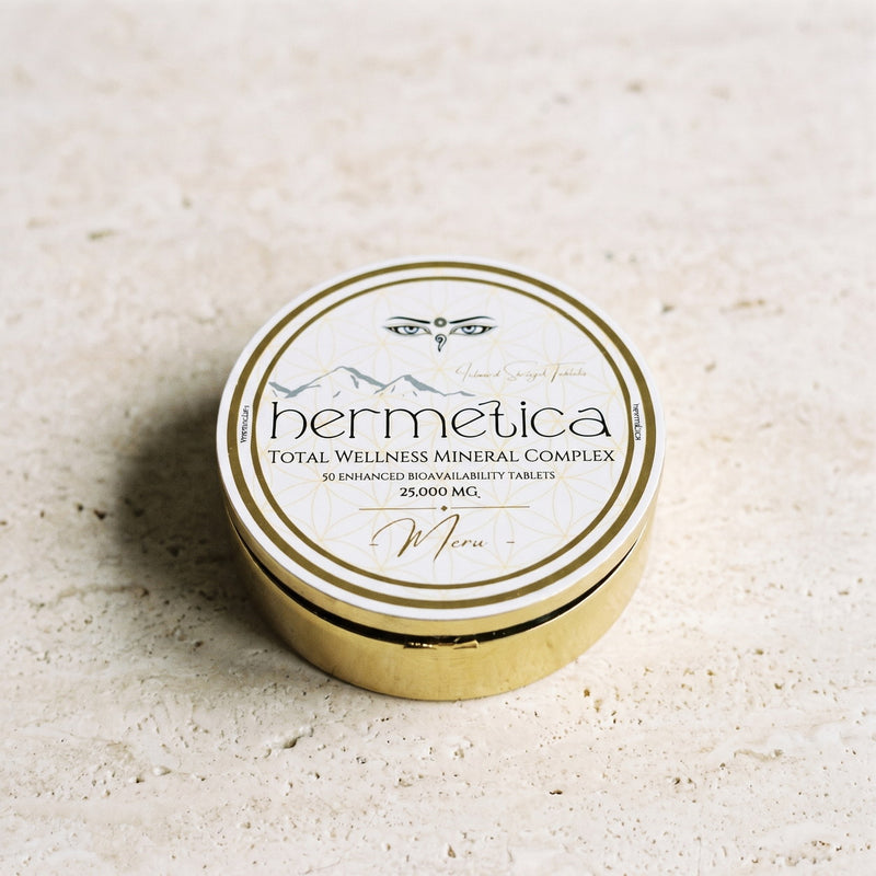 Closed gold Meru tin standing on pale travertine in soft daylight