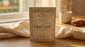 Cozy Adaptogenic Chai pouch on a wooden counter beside a steaming mug of chai