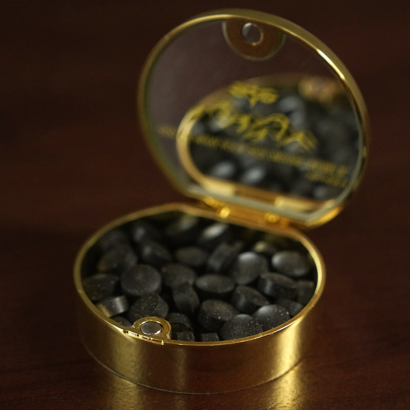 Real Meru gold compact open with black shilajit tablets and its mirrored interior lid