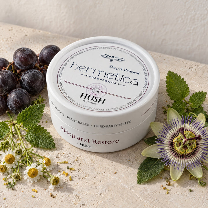 Hush Sleep Gummies tin on pale stone with a single dark purple gummy beside it